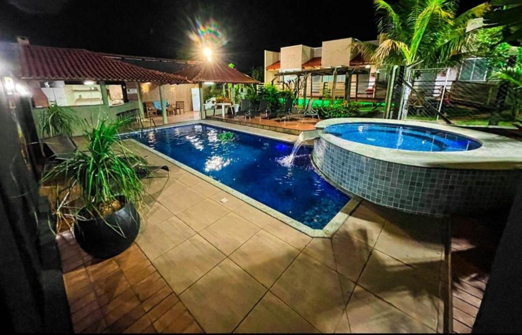 a swimming pool in a yard at night at Pousada Encantos do Glória in São João Batista do Glória