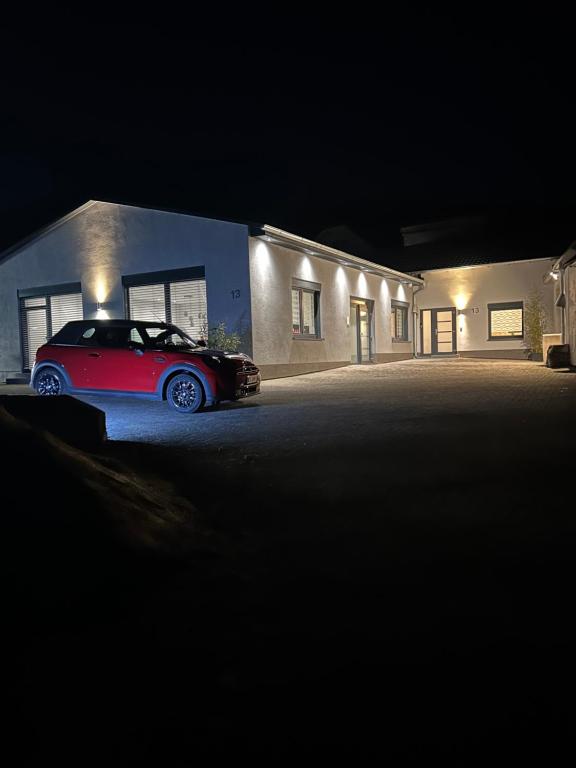 un coche rojo estacionado frente a un edificio por la noche en Ferienwohnung Ambiente 1, en Naumburg