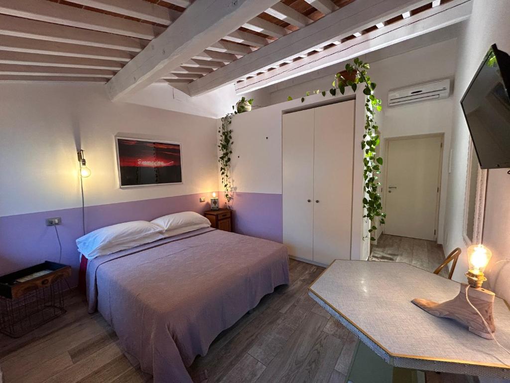 een slaapkamer met een bed en een tafel en een televisie bij Santa Marta Rooms&Studios in Verona