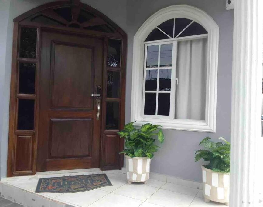 uma casa com uma porta e uma janela e duas plantas em Casa Bonita em Puerto Cortes