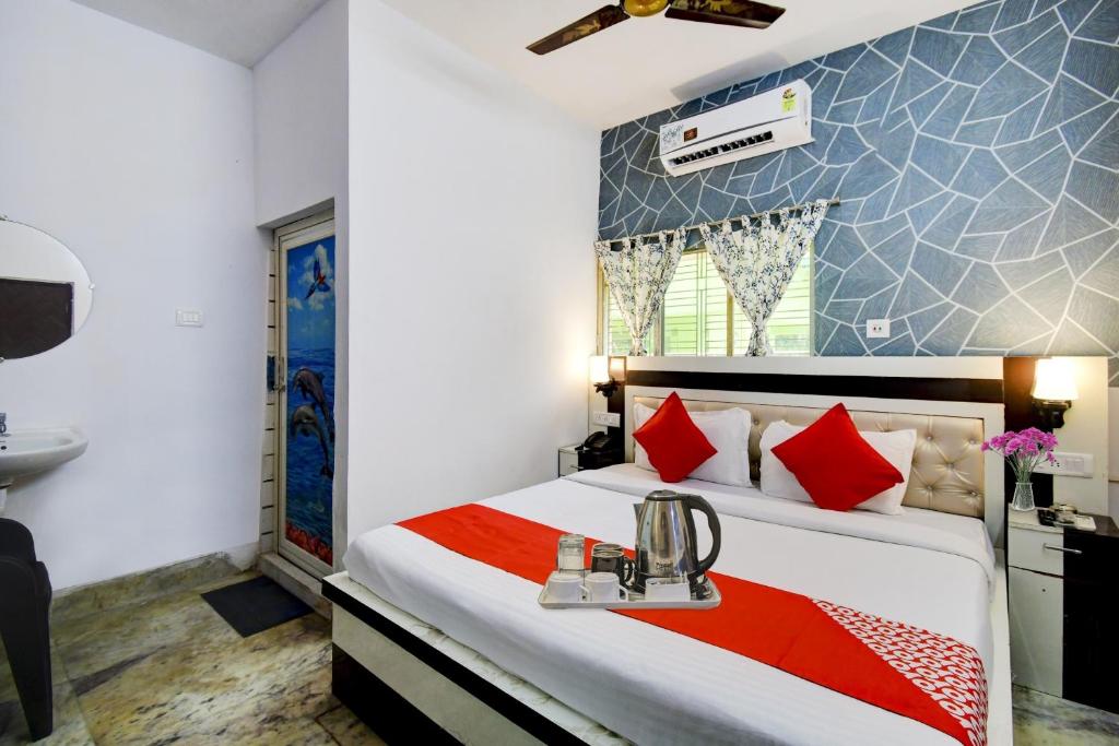 a bedroom with a bed with red pillows and a sink at OYO Flagship The Nest Inn Near Acropolis Mall in Jādabpur