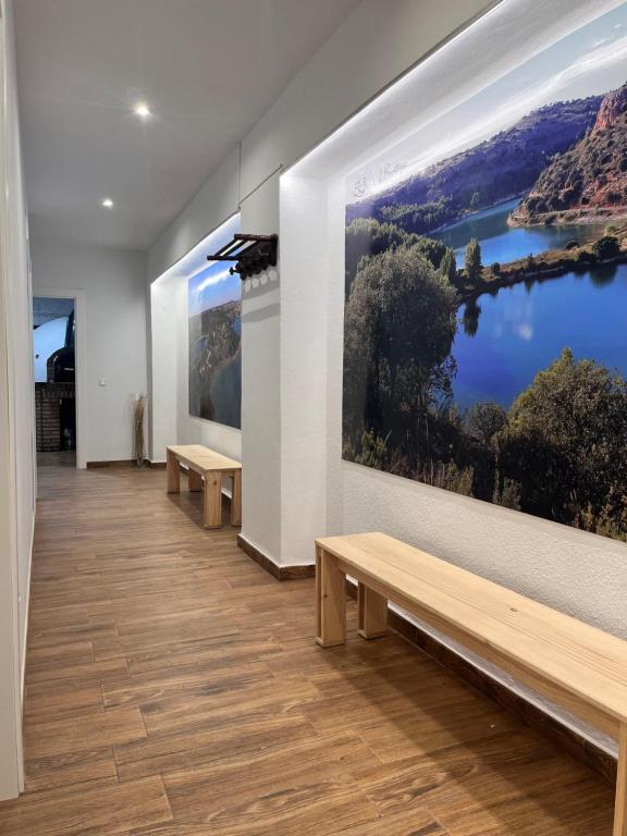 une chambre avec des bancs et un grand tableau sur le mur dans l'établissement Casa Rural Abuelo Raimundo, à Ossa de Montiel