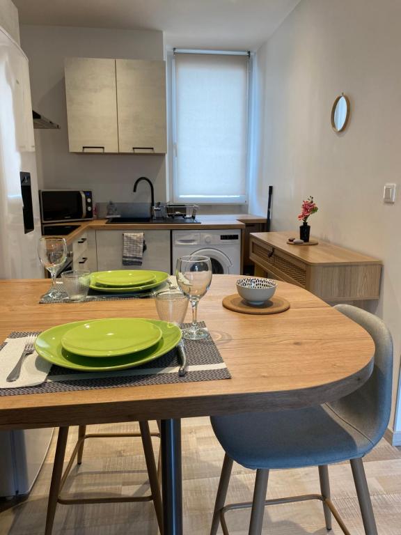eine Küche mit einem Holztisch mit grünen Tellern und Gläsern in der Unterkunft Verger - Parking gratuit - Calme in Chambéry