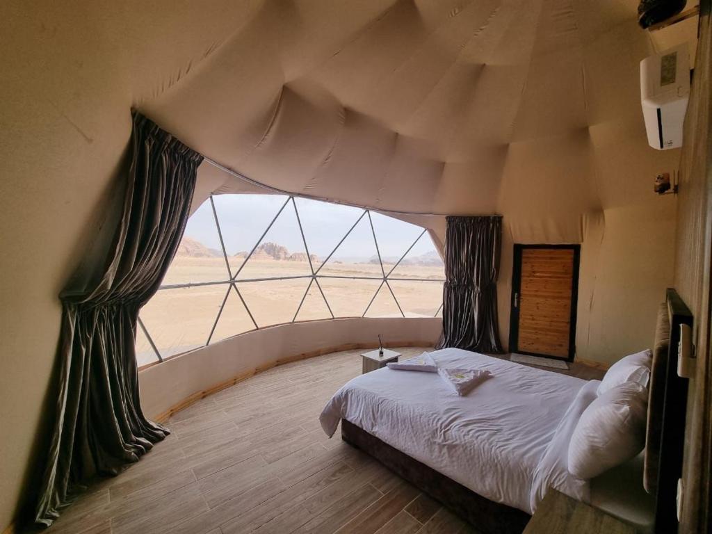 a bedroom with a bed and a large window at Rum Magic Desert in Wadi Rum