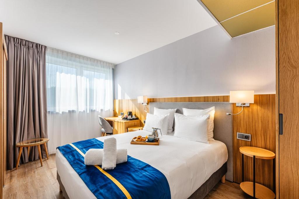 ロニー・スー・ボワにあるBrit Hotel Privilège Paris Rosny-sous-Boisの大きなベッドとデスクが備わるホテルルームです。