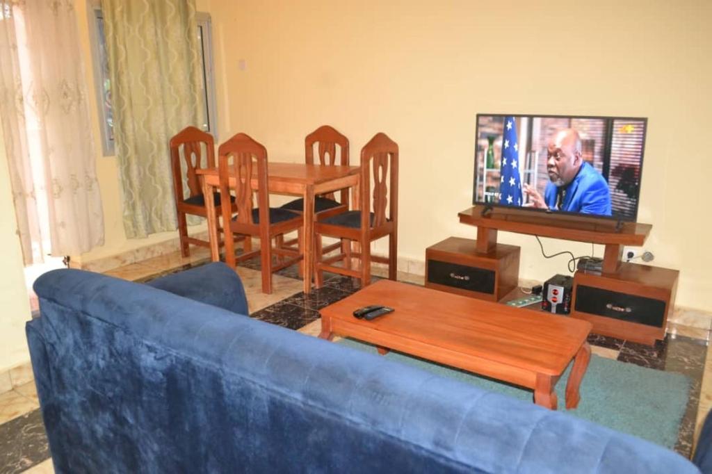 sala de estar con sofá azul, mesa y TV en Habib, en Yaoundé
