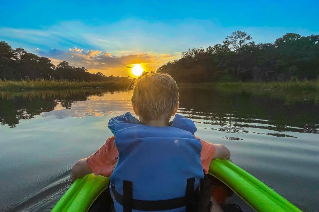 un joven en un barco en un río al atardecer en Marsh Girl Cottage, en Shallotte