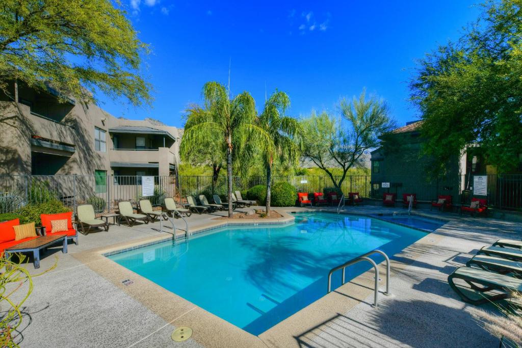 a large swimming pool with lounge chairs and trees at The Greens at Ventana Canyon #1205 in Tucson