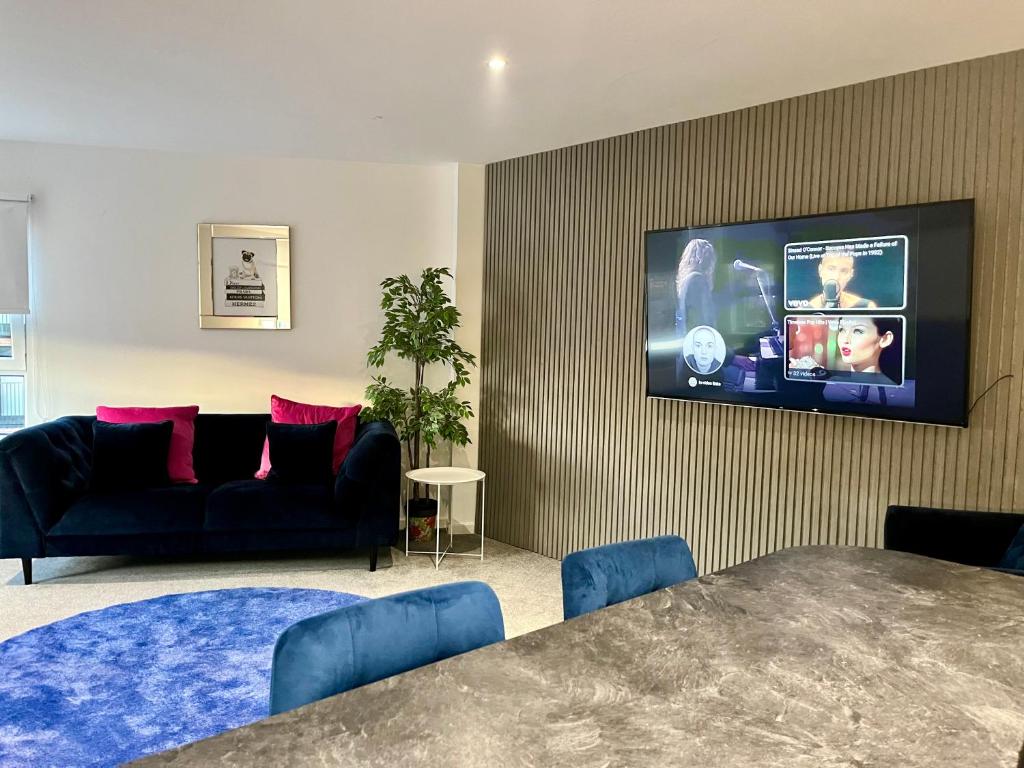 a living room with a couch and a tv on a wall at Glas-Go 2 bedroom Apartment 3 min walk to SECC Hydro FREE PARKING ONSITE in Glasgow