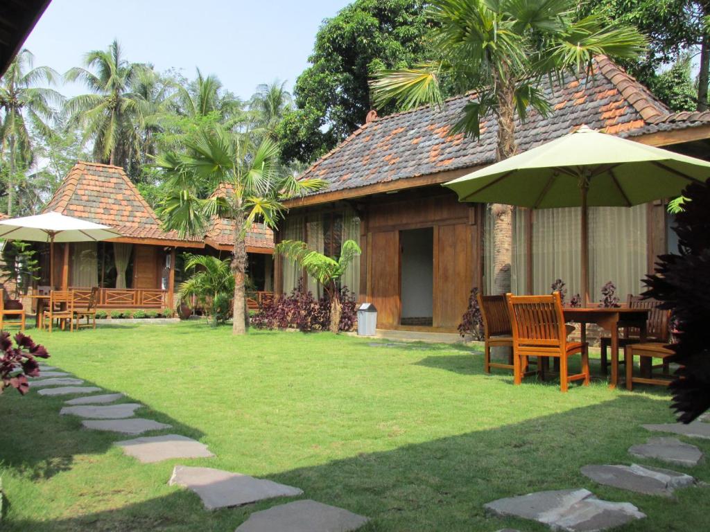 a house with tables and umbrellas in a yard at Cempaka Villa in Borobudur