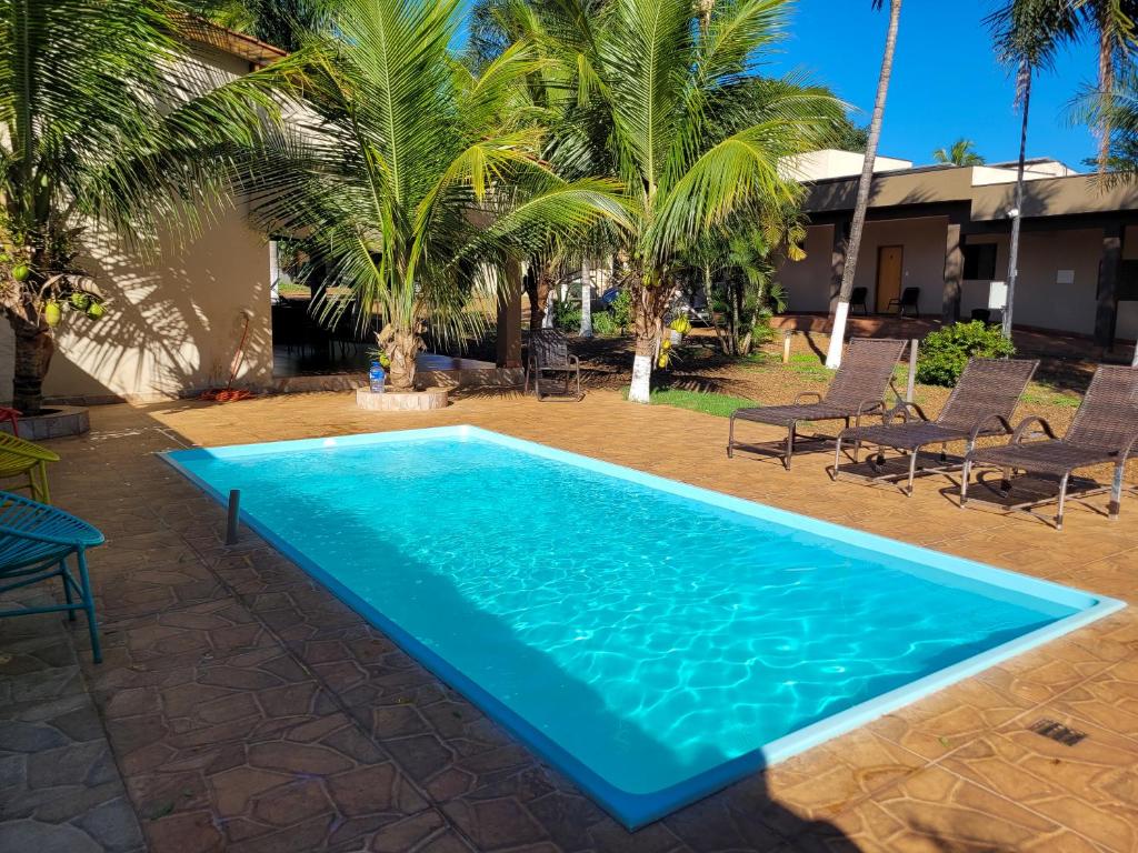 a pool in the backyard of a house with palm trees at Pousada Recanto Flor de Lótus in Olímpia