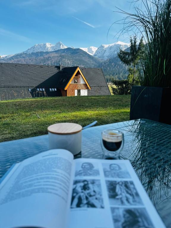 an open book on a table with a house in the background at Podhalańskie Marzenie by Apart Concept Podhale in Kościelisko