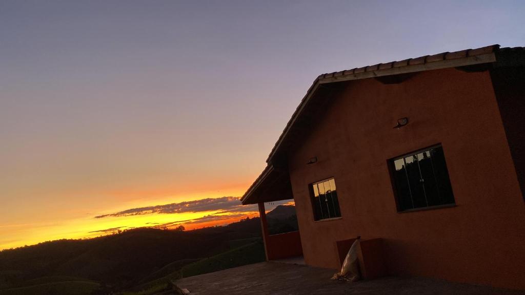 a building with the sunset in the background at Sítio Ramos casa da montanha in Cunha