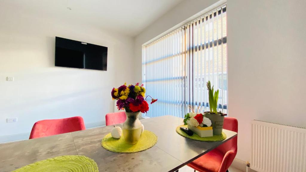 einen Esstisch mit einer Blumenvase darauf in der Unterkunft Shadwell - walking distance to Tower Bridge, two stations in close proximity in London