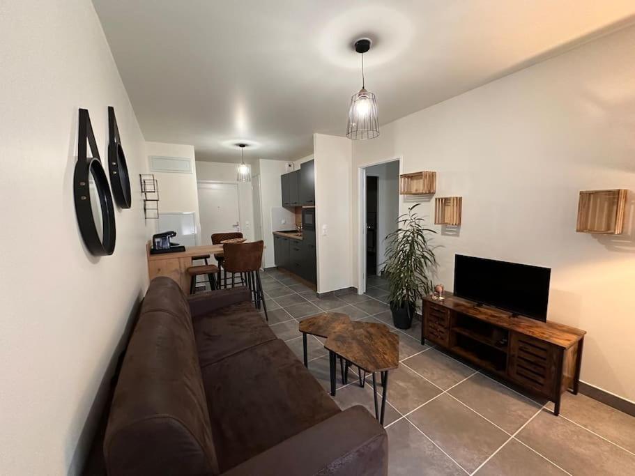 a living room with a brown couch and a kitchen at A 600m de la plage - Le Cosy - in Mimizan