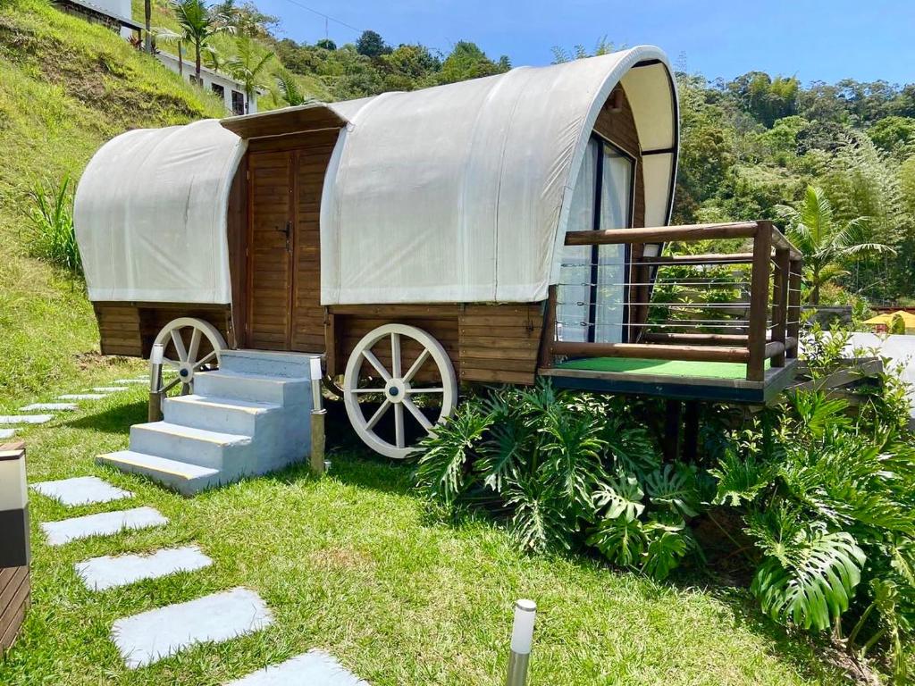 a wooden wagon with a cover on top of a hill at Glamping La Cepa GUATAPÉ in Guatapé