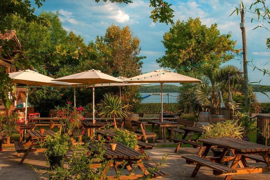 a group of picnic tables and umbrellas at a restaurant at La cabane du lac in Aureilhan