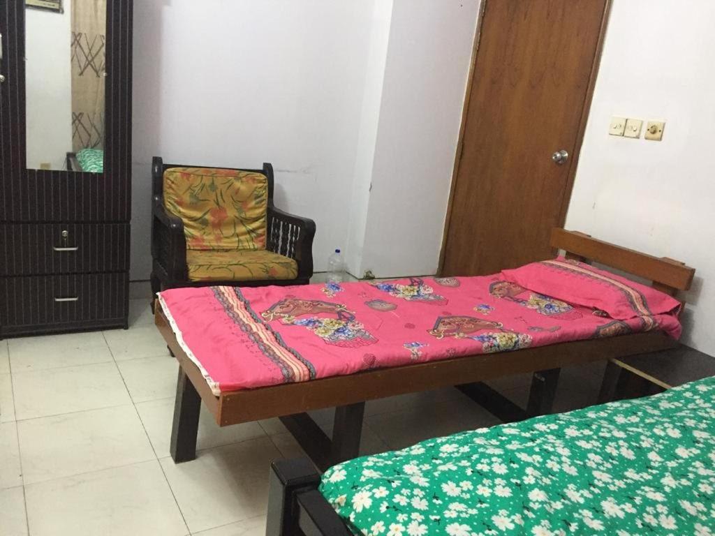 una camera con due letti e una sedia di Rainbow Guest House a Dhaka