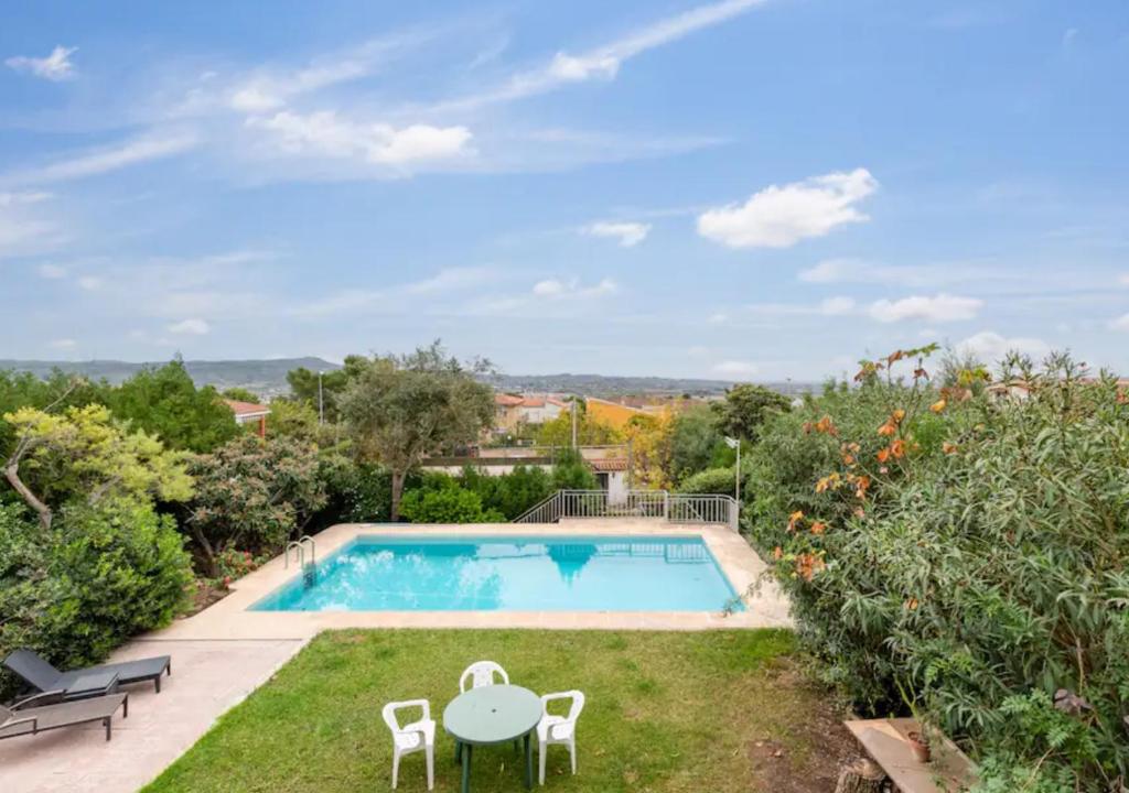 un patio trasero con piscina, mesa y sillas en Charming house with private tennis court and pool, en Catadau