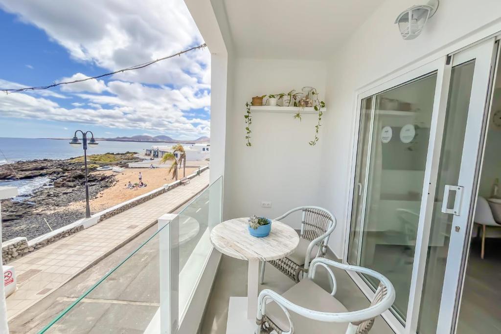 een balkon met een tafel en uitzicht op het strand bij Casa Burgao n5 on the front line with seaview terrace in Punta de Mujeres