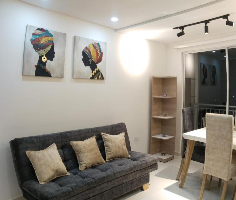 a living room with a couch and paintings on the wall at Encantador apartamento con aire in Neiva
