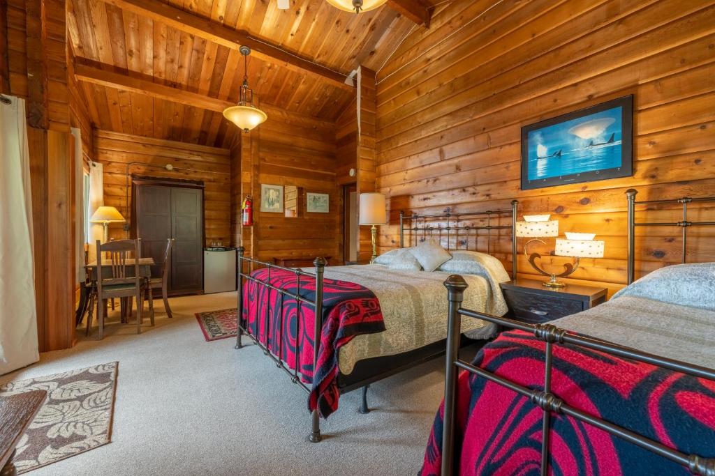 a bedroom with two beds in a room with wooden walls at Alert Bay Lodge in Alert Bay