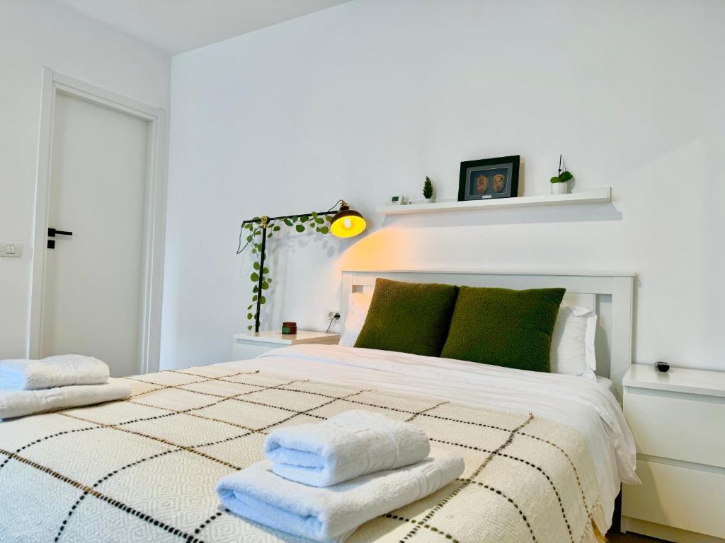 ein weißes Schlafzimmer mit einem Bett mit Handtüchern darauf in der Unterkunft Sky Residence Airport Otopeni no 1 in Otopeni