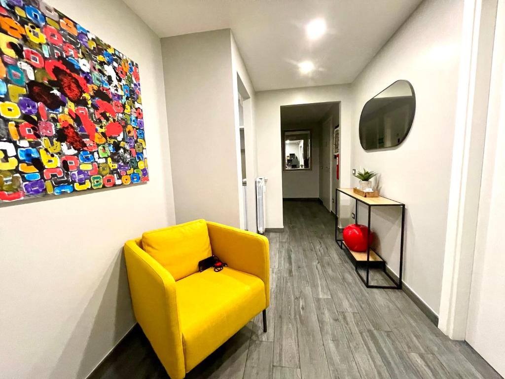 a yellow chair in a hallway with a painting on the wall at Your House By Ale in Rome