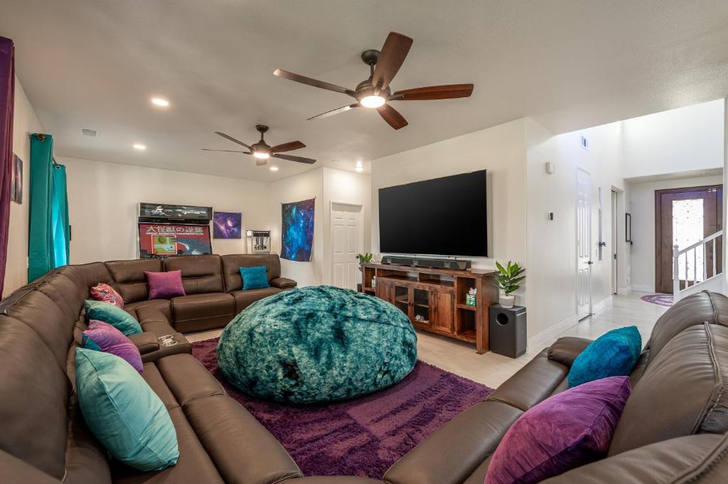a living room with a couch and a flat screen tv at Coachella Play - 6BR Multi-Gen Fun Zone and Retreat with free heated pool in Indio