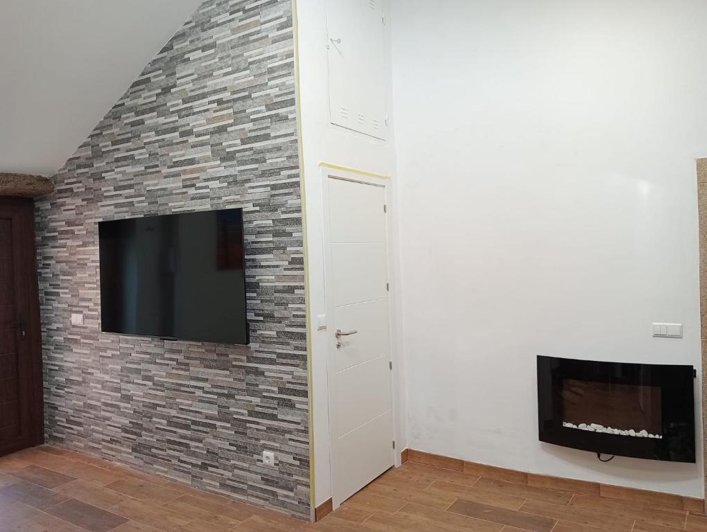 a living room with a brick wall with a flat screen tv at Casa Rueiro in A Pobra do Caramiñal
