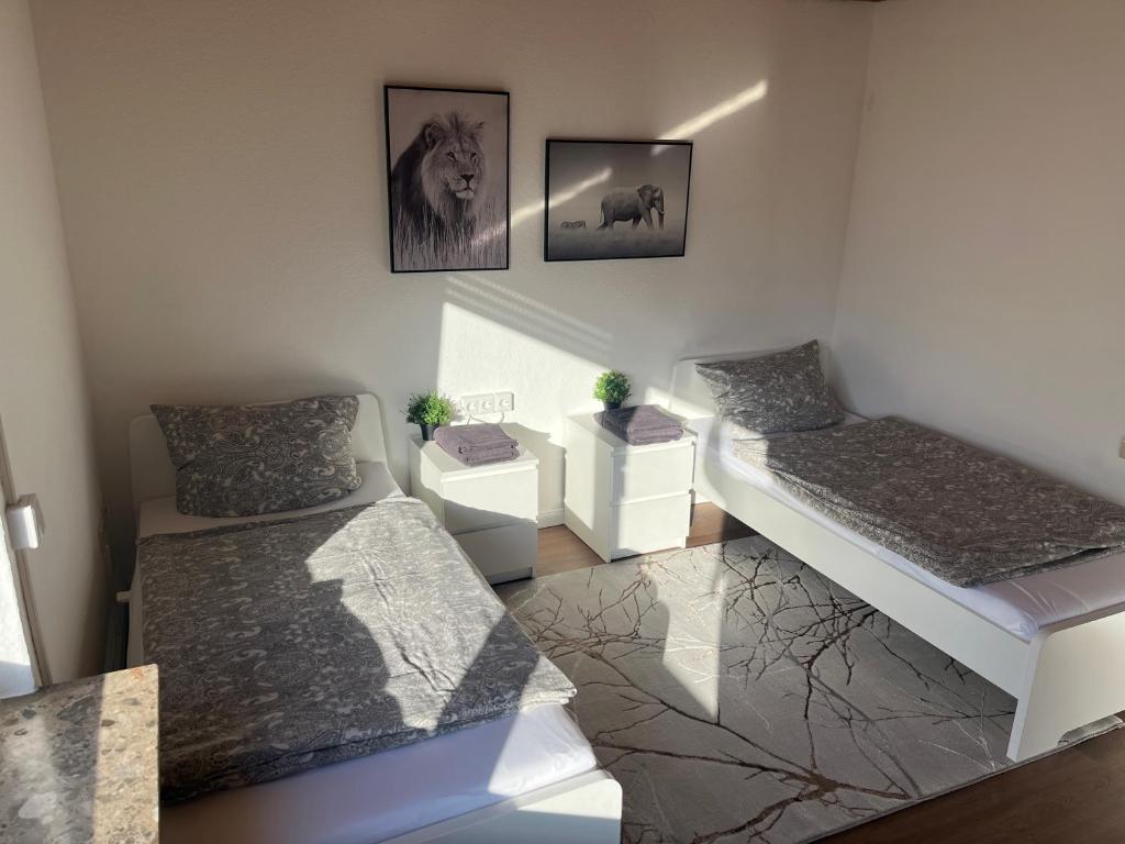 Habitación pequeña con 2 camas y cuadros en la pared. en Weber Apartment Luisa, en Bohmte