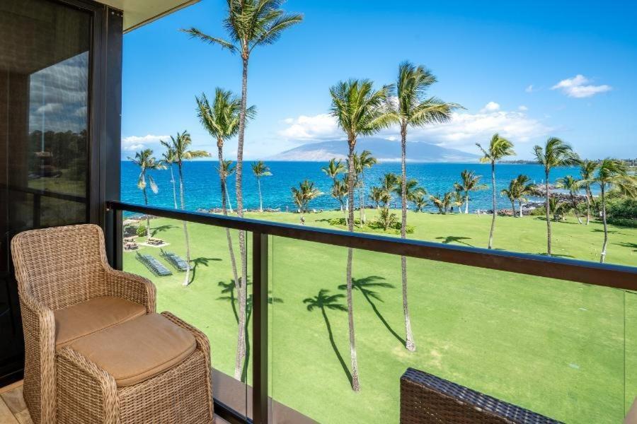a balcony with a view of the ocean and palm trees at KIHEI SURFSIDE, #512 condo in Wailea