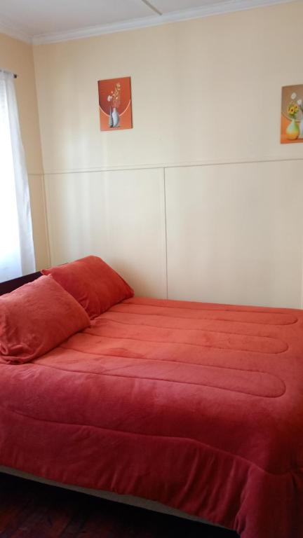 a bedroom with a red bed with a red blanket at hostal RV in Temuco