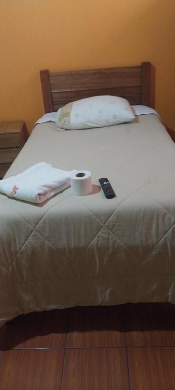 a bed with a remote control and a cup on it at HOSTAL JOYA ANDINA in Puno