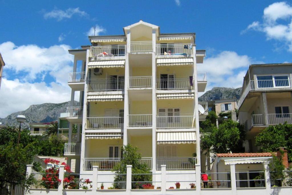 un edificio giallo alto con balconi bianchi di Apartments by the sea Podgora, Makarska - 2615 a Podgora