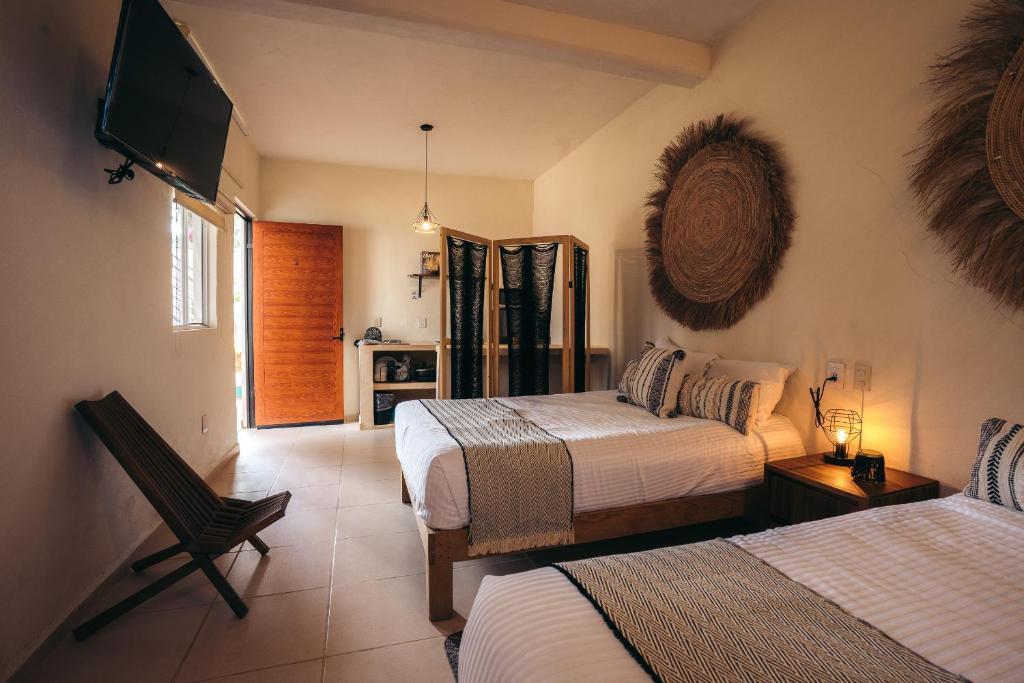 a bedroom with two beds and a flat screen tv at Nuiya Hoteles Centro in Sayulita