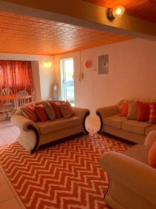 a living room with two couches and a rug at Lovely 2 bedroom condo with WiFi in a quiet area, 7-10 minutes away from both the airport and Oistins in Christ Church