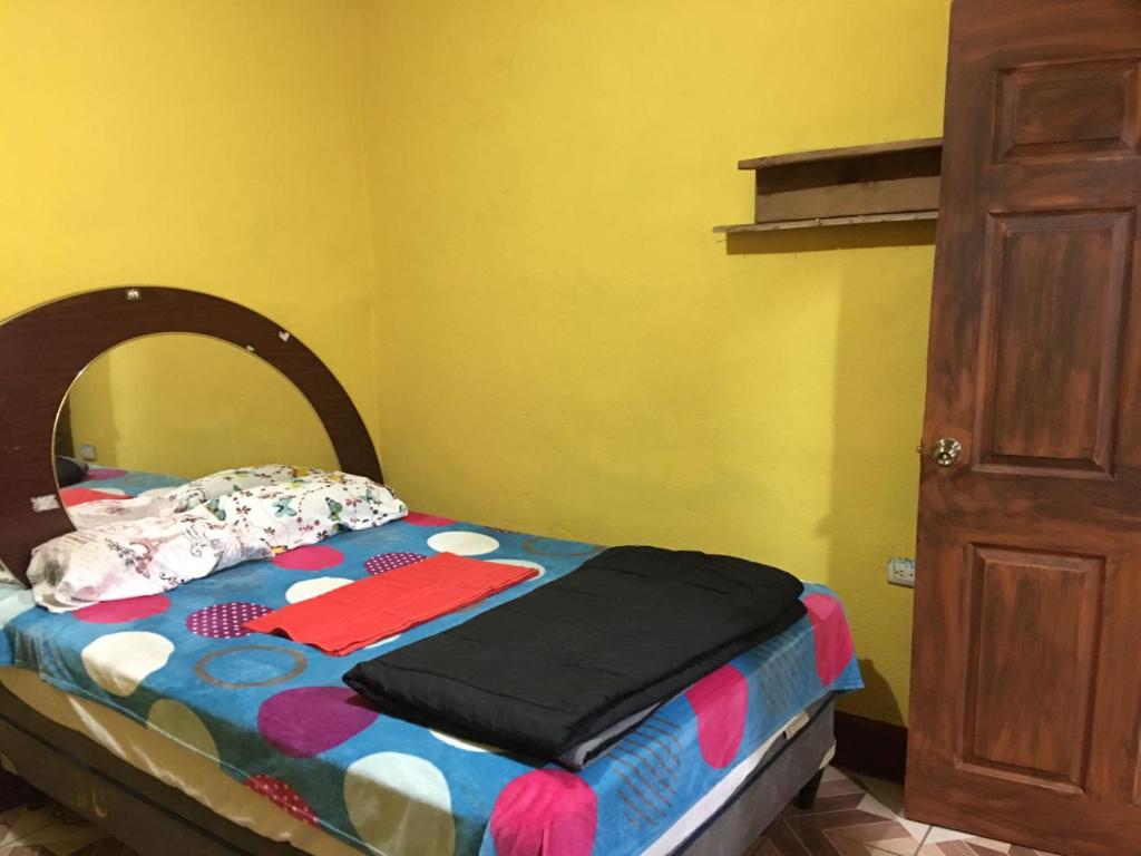 Cama pequeña en habitación con pared amarilla en Hostal Candelaria en San Juan La Laguna