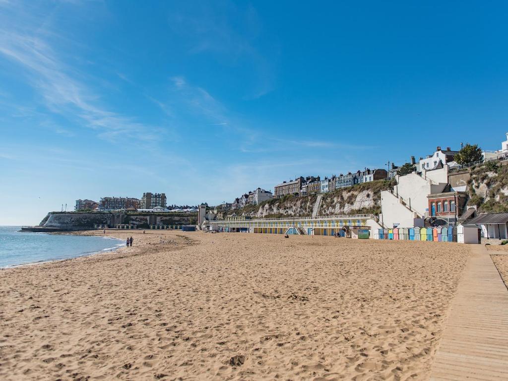 a sandy beach with buildings and the ocean at Casa Musica in Broadstairs