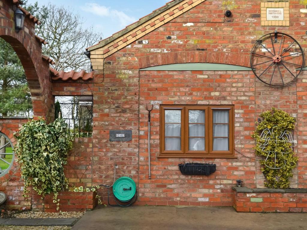 a brick house with a window and a green door at Oak Cottage - Uk46261 in Tetney