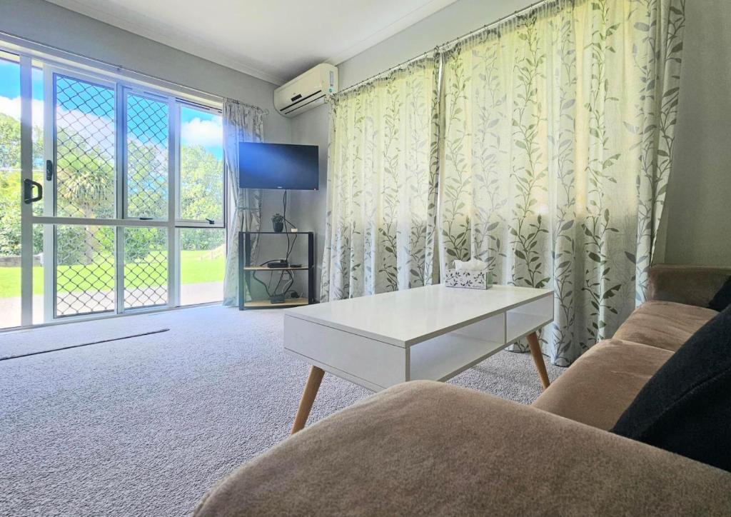 ein Wohnzimmer mit einem Sofa und einem Tisch in der Unterkunft Cozy Private Villa in Oropi in Oropi