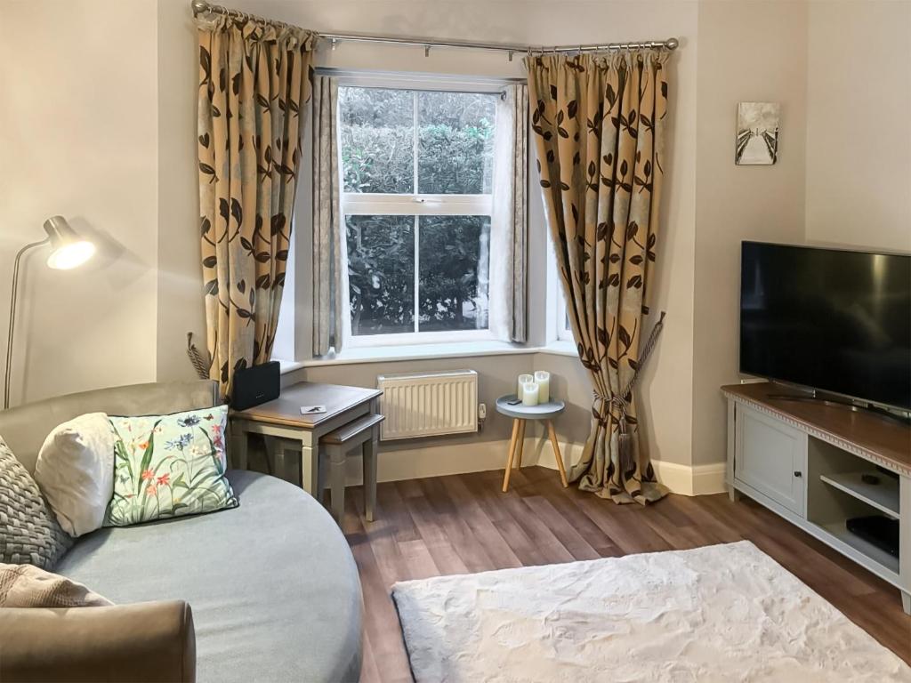 a living room with a couch and a tv and a window at Melrose Walk in Tewkesbury