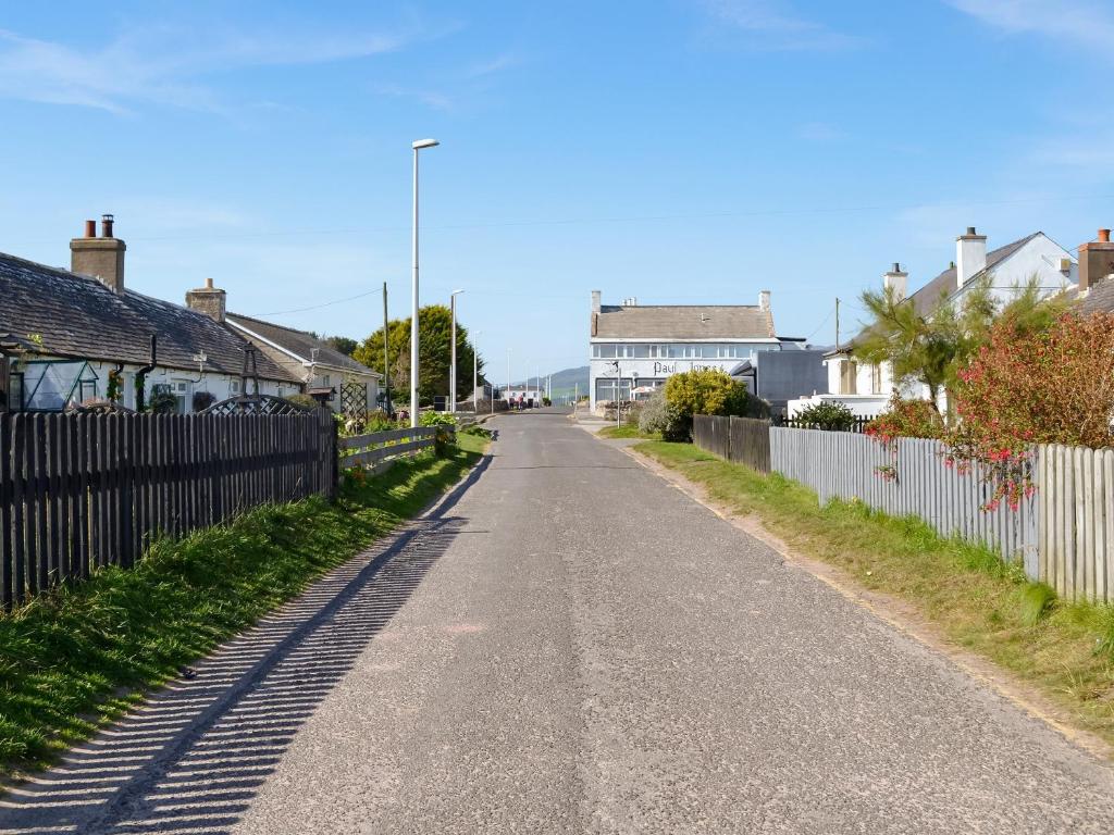 an empty street with houses and a fence at Kadelin Cove in Mainsriddle