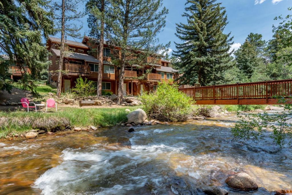 a bridge over a river in front of a house at Stonebrook Resort - Adult Only in Estes Park