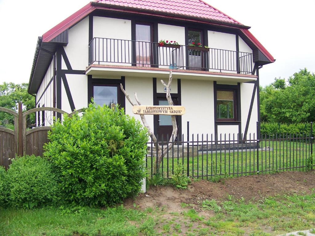 uma casa branca com uma varanda e uma cerca em Agroturystyka W Jabłoniowym Sadzie em Jeżyce