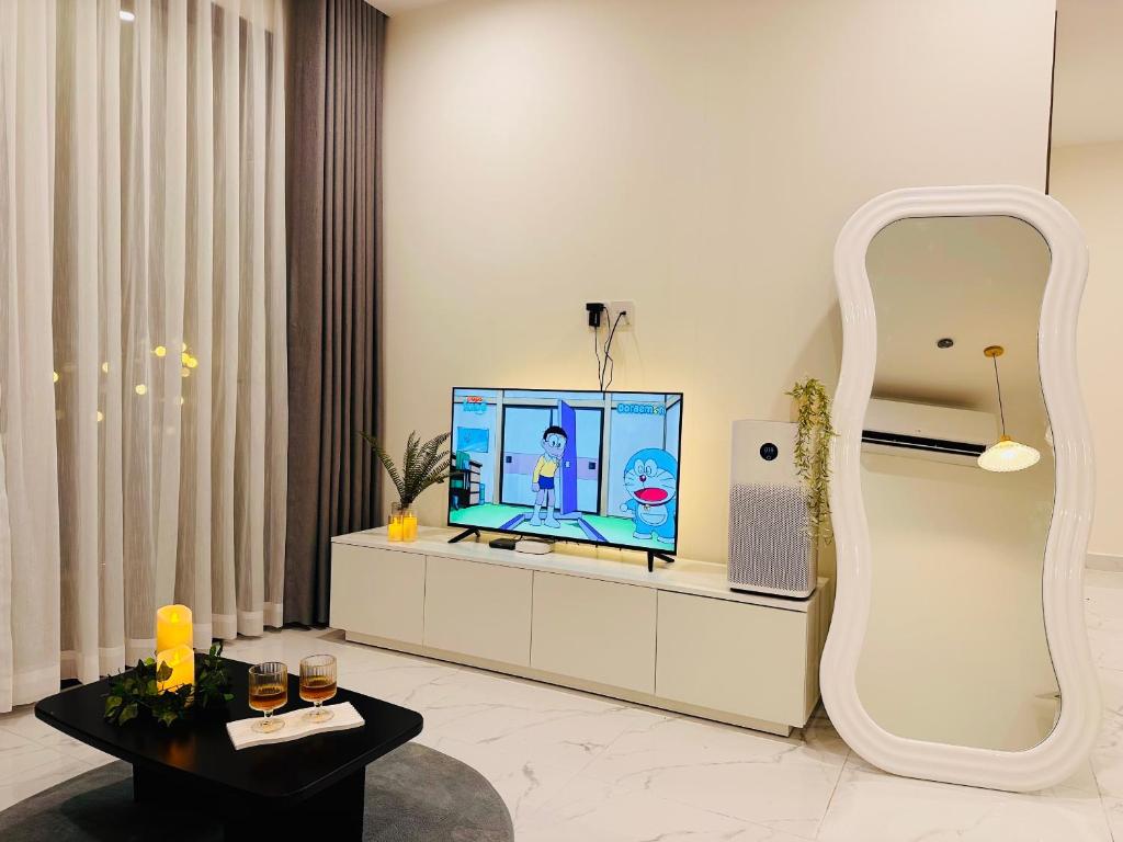 a living room with a television on a white cabinet at Vinhomes Grand Park - FEBRUARYroom in Gò Công