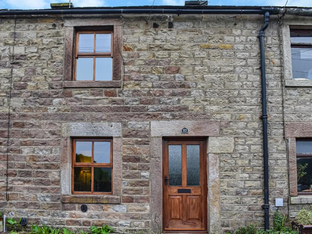 a brick building with a wooden door and windows at Hill View Cottage in Galgate