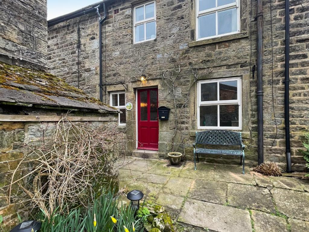 a brick house with a red door and a bench at Middle Cottage in Middlesmoor