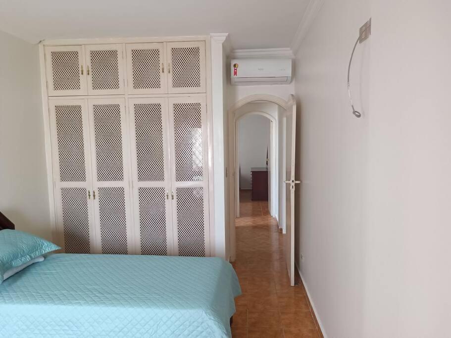 een slaapkamer met een bed en een deur naar een gang bij Apartamento Guarujá Pitangueiras in Guarujá