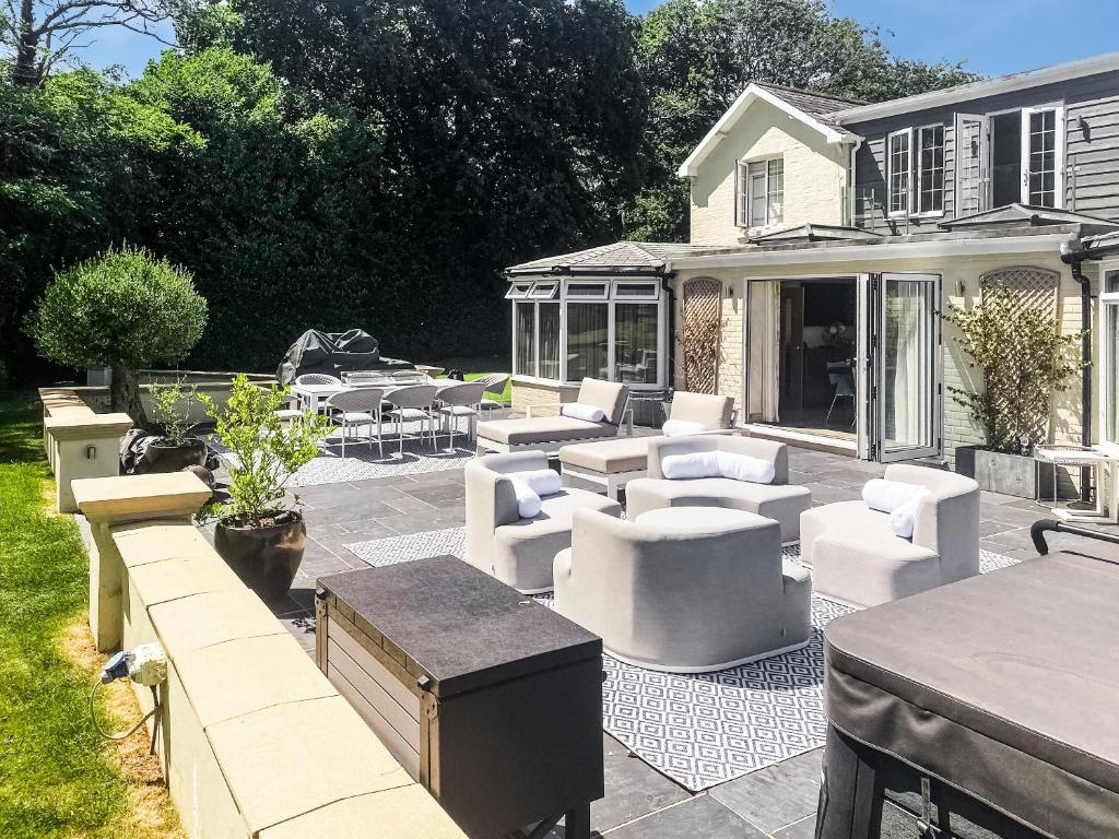 a patio with couches and chairs in front of a house at Woodlea Farm in Four Marks